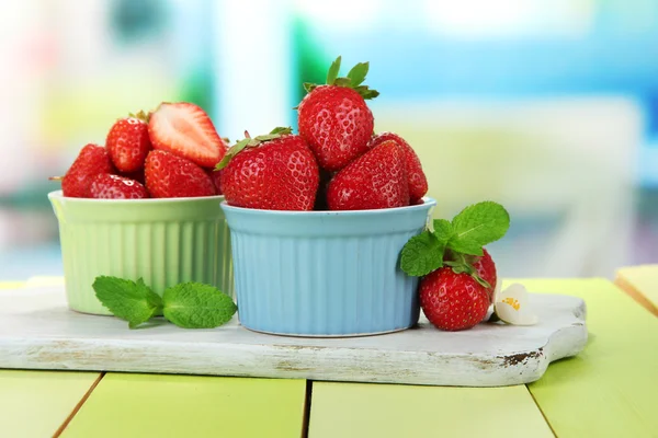 Reife süße Erdbeeren in Schalen auf grünem Holztisch — Stockfoto