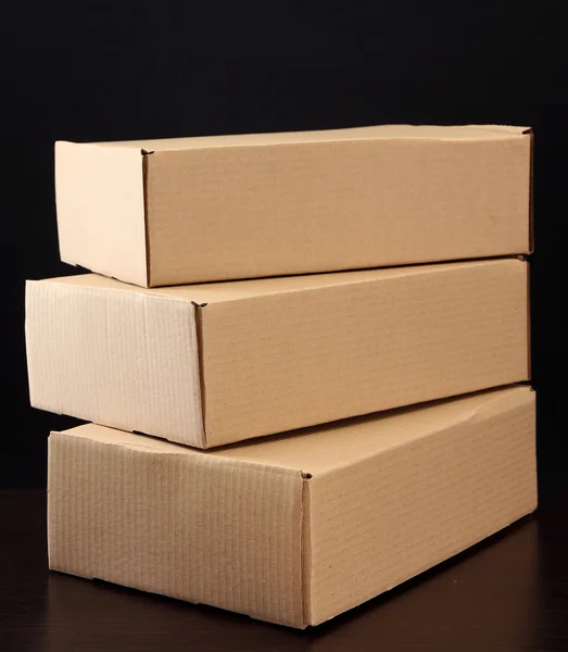 Cajas de paquetes sobre mesa de madera, sobre fondo negro — Foto de Stock