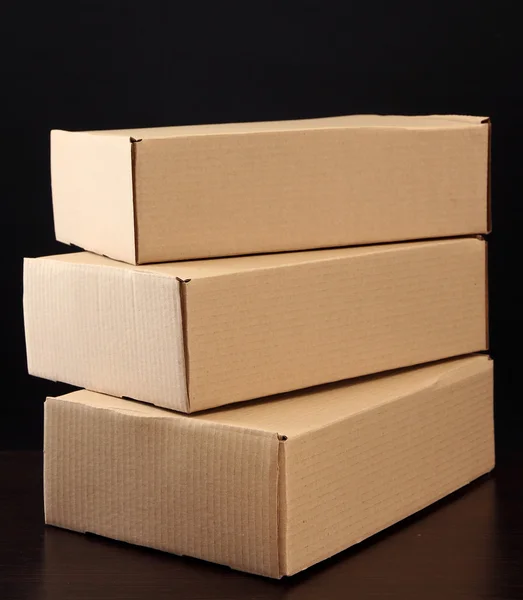 Parcels boxes on wooden table, on black background — Stock Photo, Image