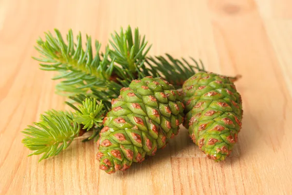 Green cones and fir tree on wooden background — Stock Photo, Image