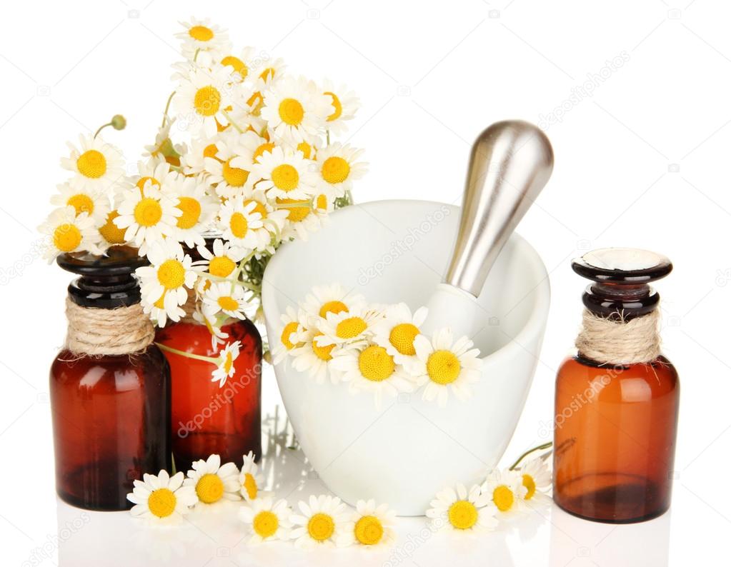 Essential oil and chamomile flowers in mortar isolated on white