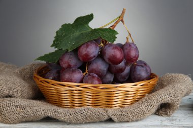 hasır sepet tabloda gri arka plan üzerinde olgunlaşmış lezzetli üzüm
