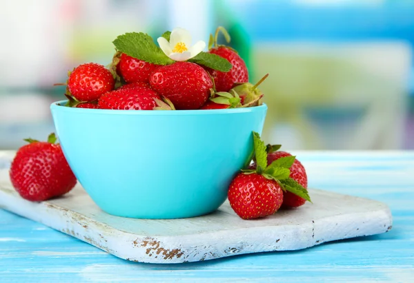 Rijpe zoete aardbeien in kom op blauwe houten tafel — Stockfoto
