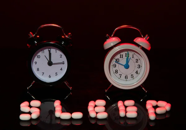 Relojes y píldoras de alarma de estilo antiguo, sobre fondo oscuro — Foto de Stock