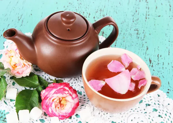 Waterkoker en kopje thee uit de thee rose aan boord op servet op houten achtergrond — Stockfoto