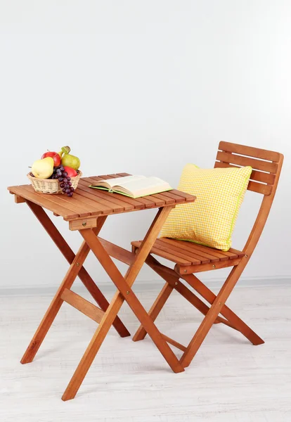 Wooden table with fruit and book on it in room — Stock Photo, Image