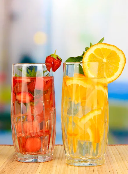 Glasses of fruit drinks with ice cubes on table in cafe — Stock Photo, Image