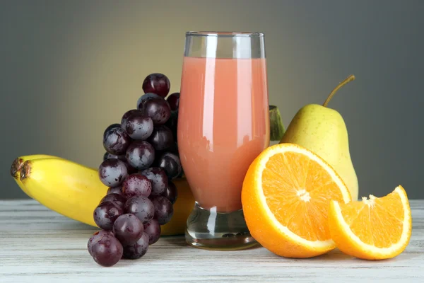 Glass of fresh juice on table on gray background — Stock Photo, Image