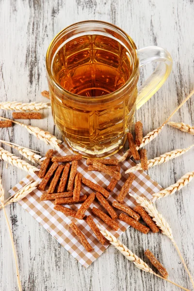 Cerveja em vidro e crostas em guardanapo na mesa de madeira — Fotografia de Stock