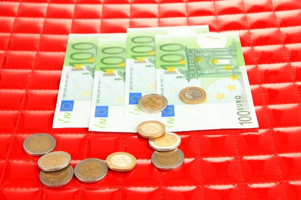 Euro banknotes and euro cents on red background — Stock Photo, Image