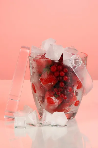 Frozen berries in bucket of ice on color background — Stock Photo, Image