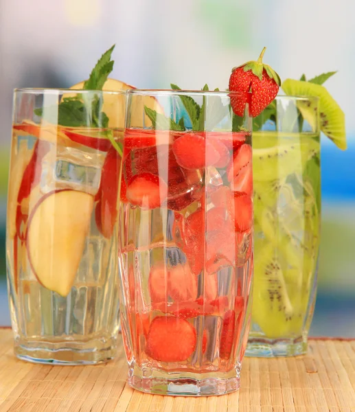 Glasses of fruit drinks with ice cubes on table in cafe — Stock Photo, Image