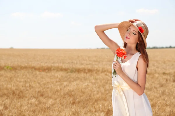 Portret van mooie jonge vrouw met papavers op het gebied — Stockfoto