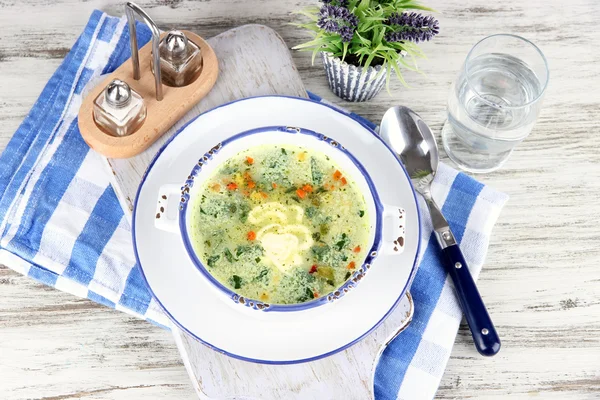 Soup in plate on napkin on wooden board on table — Stock Photo, Image