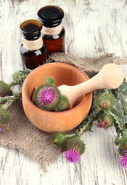 Botellas de medicina y mortero con flores de cardo sobre fondo de madera —  Fotos de Stock