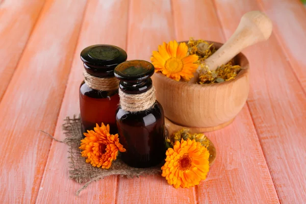 Garrafas de medicina e flores de calêndula em fundo de madeira — Fotografia de Stock