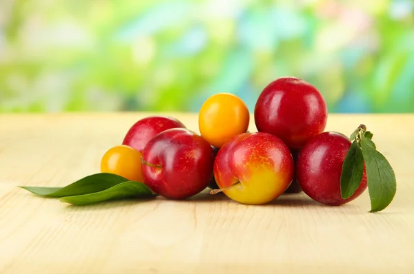 Ripe plums on wooden table on natural background — Stock Photo, Image