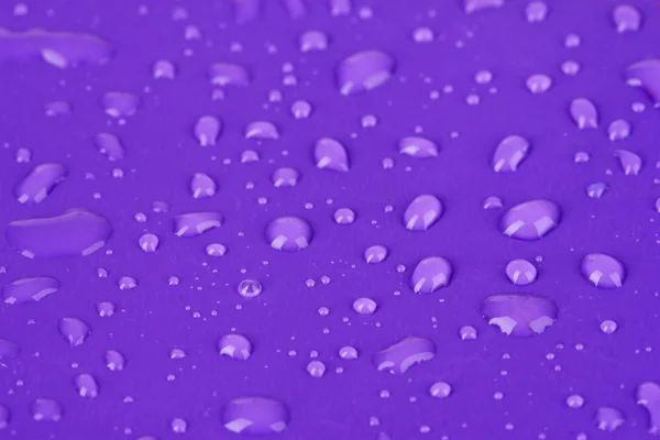 Gotas de agua sobre fondo plástico púrpura — Foto de Stock