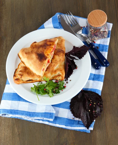 Pizza calzone on plates on napkin on wooden table — Stock Photo, Image