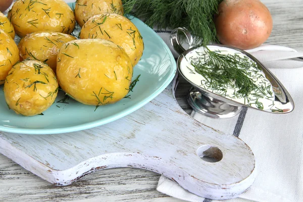 Boiled potatoes on platen on wooden board near napkin on wooden table — Stock Photo, Image