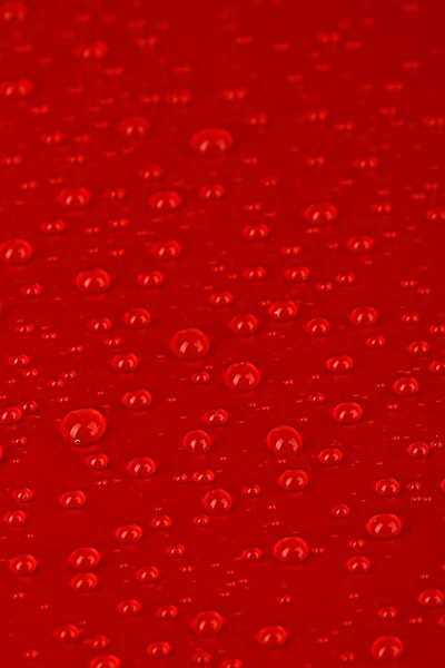 Gotas de água no fundo de plástico vermelho — Fotografia de Stock