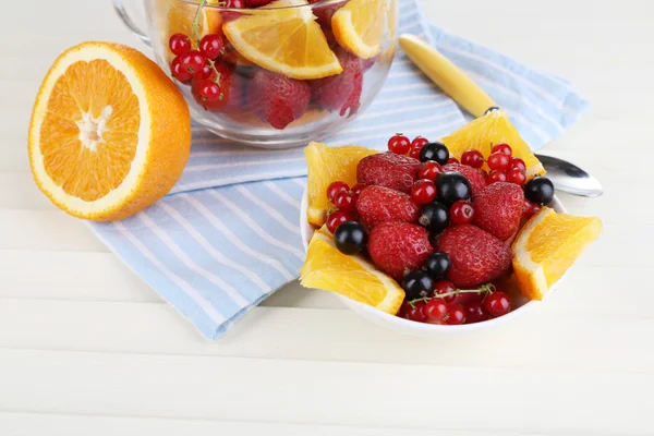 Salade de fruits utile dans une tasse en verre et un bol sur une table en bois close-up — Photo