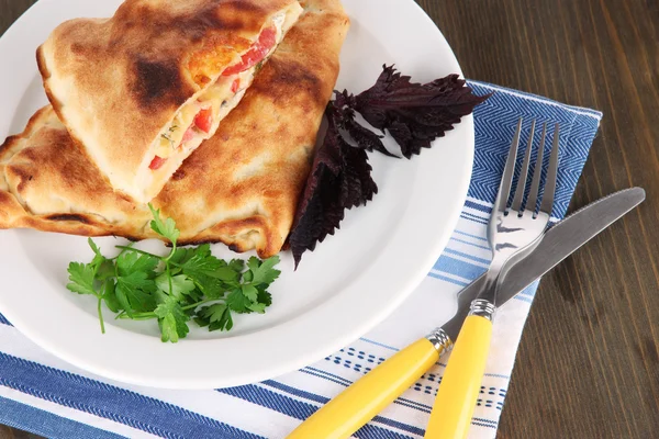 Pizza calzone na štítku na ubrousek na dřevěný stůl — Stock fotografie