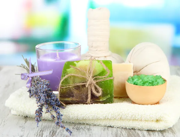 Natureza morta com vela de lavanda, sabão, bolas de massagem, garrafas, sabão e lavanda fresca, na mesa de madeira no fundo brilhante — Fotografia de Stock