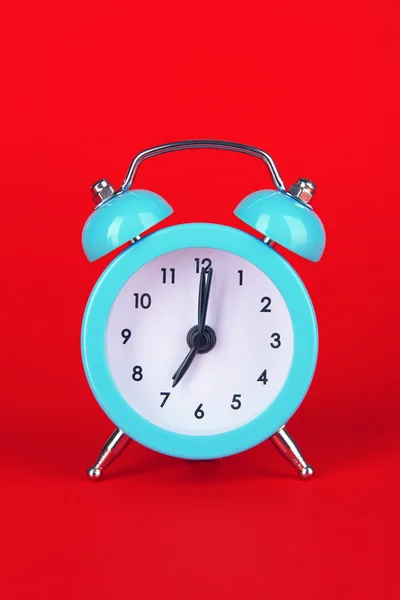 Ceas deșteptător albastru pe fundal roșu — Fotografie, imagine de stoc