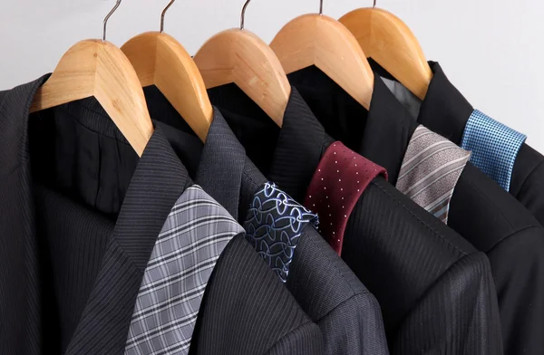 Suits and ties on hangers on gray background — Stock Photo, Image