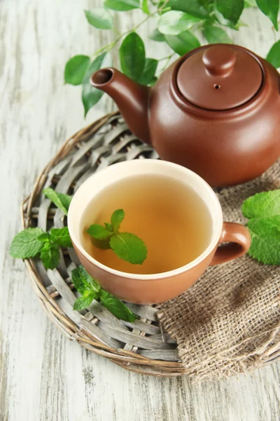Teekanne und Tasse Kräutertee mit frischer Minze auf Holztisch — Stockfoto