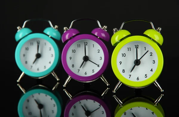 Reloj despertador colorido sobre fondo gris oscuro —  Fotos de Stock