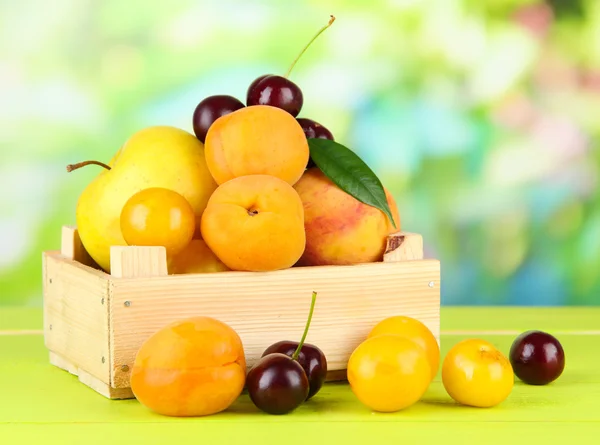 Frutas brilhantes de verão em caixa de madeira na mesa de madeira em fundo natural — Fotografia de Stock