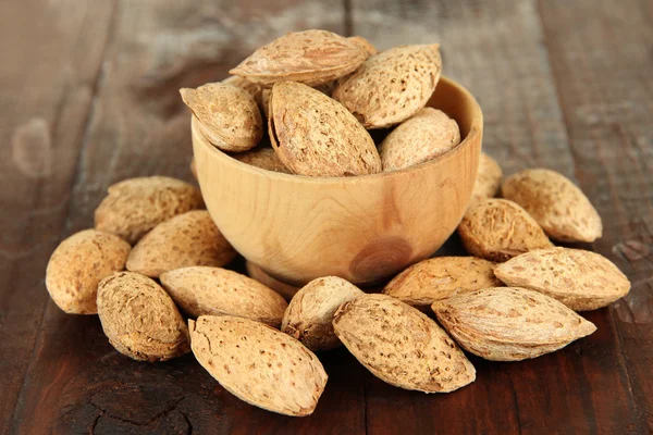 Almond in wooden bowl, on wooden background — Stock Photo, Image