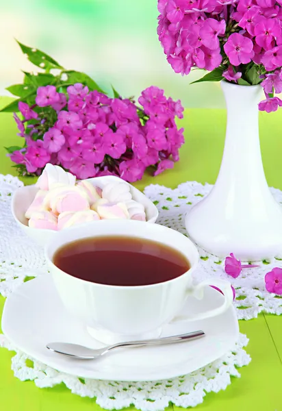 Hermoso ramo de flox con taza de té en la mesa sobre fondo claro — Foto de Stock