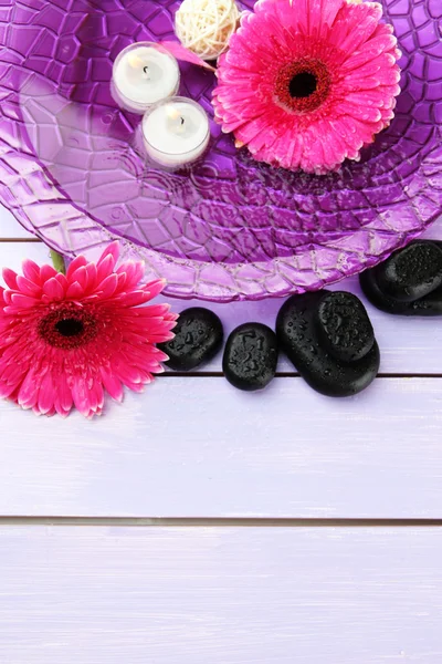 Wellness-Steine, schöne Gerbera-Blumen und Kerzen auf dem Wasser — Stockfoto