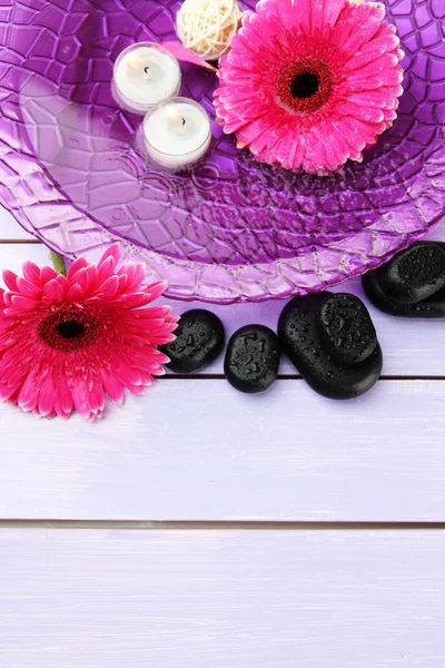 Piedras de spa, hermosas flores de gerberas y velas en el agua — Foto de Stock