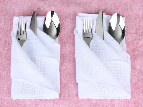 Folded napkin with fork, spoon and knife on color background — Stock Photo, Image