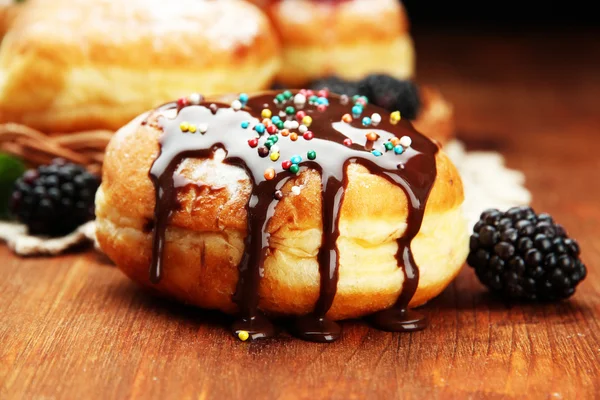 Smakelijke donuts met chocolade en bessen op houten tafel — Stockfoto