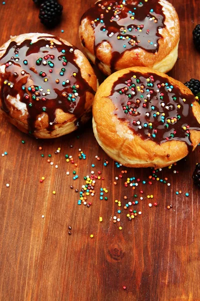与巧克力和浆果木桌上的美味甜甜圈 — 图库照片