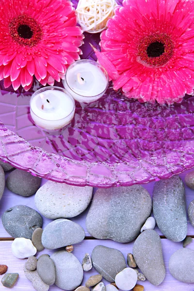 Beautiful gerbera flowers, stones and candles on water — Stock Photo, Image