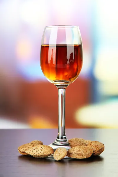 Glass of amaretto liquor and roasted almonds, on bright background — Stock Photo, Image