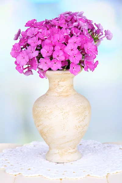 Bellissimo bouquet di phlox in vaso su tavolo su sfondo chiaro — Foto Stock