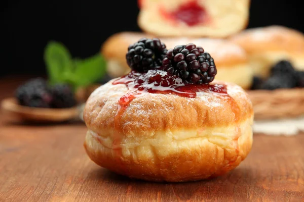 Donuts saborosos com bagas na mesa de madeira — Fotografia de Stock