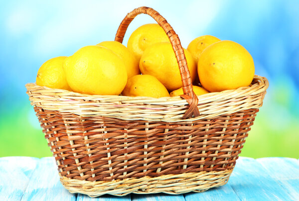 Ripe lemons in wicker basket on table on bright background