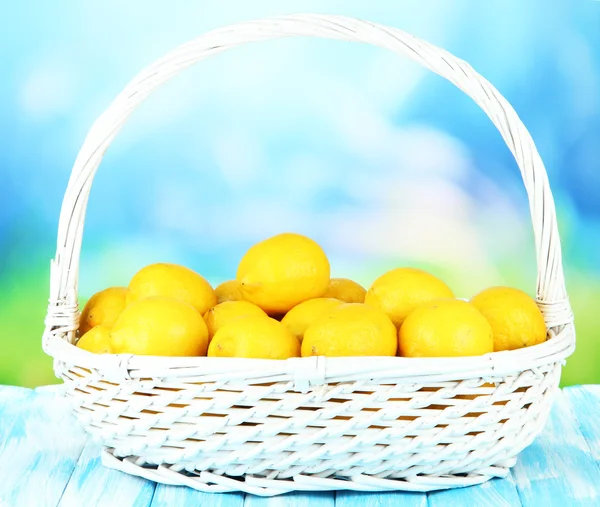 Limones maduros en canasta de mimbre sobre mesa sobre fondo brillante —  Fotos de Stock