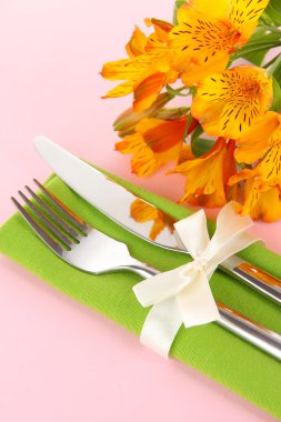 çiçekli pembe bir arka plan üzerinde şenlikli yemek masası ayarı