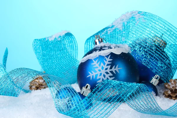 Hermosas bolas de Navidad azul y conos en la nieve sobre fondo azul —  Fotos de Stock