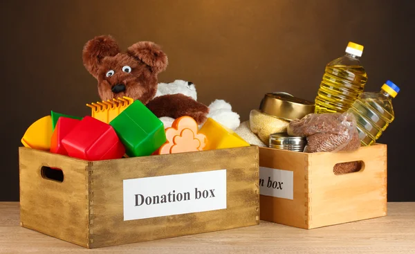 Scatola di donazione con cibo e giocattoli per bambini su sfondo marrone primo piano — Foto Stock