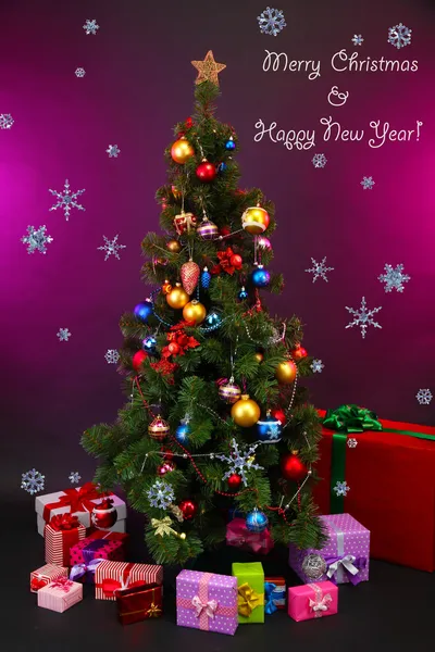 Decorated Christmas tree with gifts on purple background — Stock Photo, Image